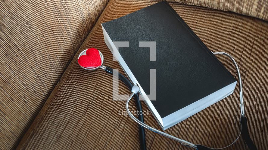 stethoscope and red felt heart on a Bible 