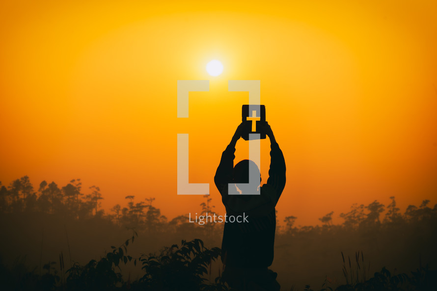 silhouette of a boy praying outdoors at sunset 