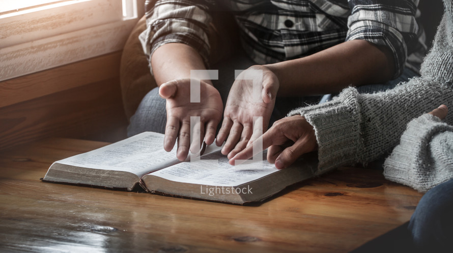 two people reading a Bible at a table 