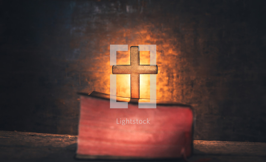 glowing cross behind a Bible 