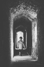 a little boy walking down a stone hallway 