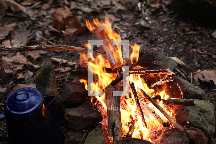 brewing coffee and roasting hot dogs by a campfire 