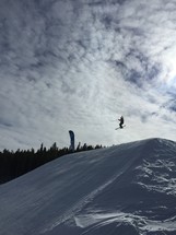 A snow skier flying over a jump.