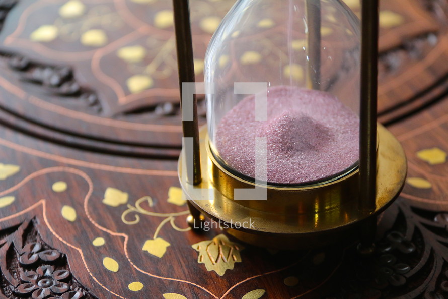 Sand running through an antique hour glass measuring time