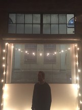 A man standing under a string of lights.