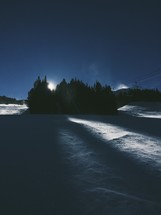 Moonlight shining through trees in a winter landscape.