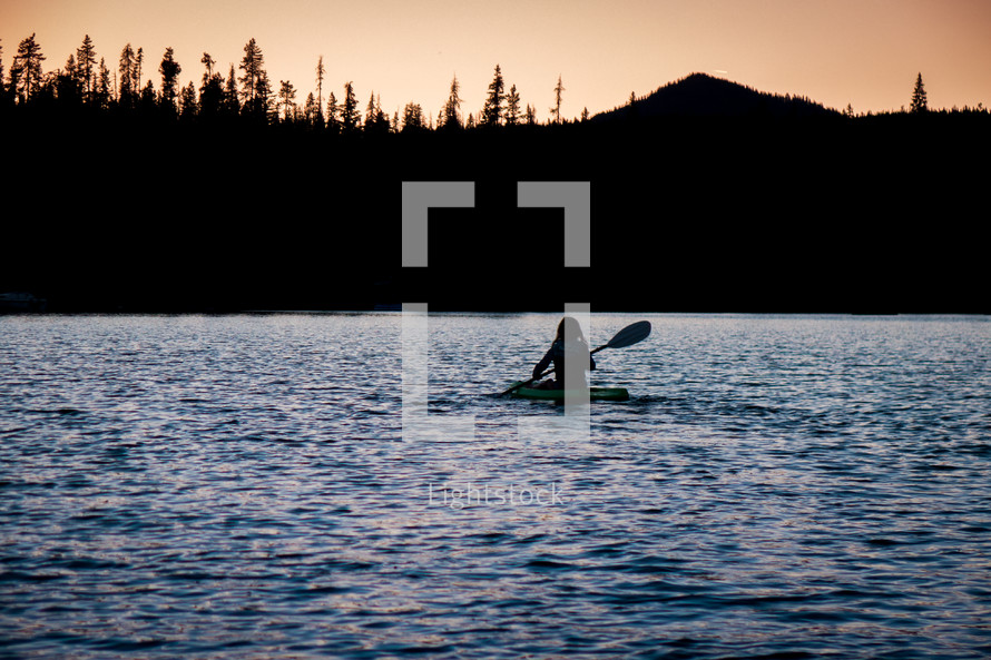 paddling in a lake at sunset 