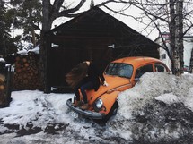 woman sitting on a Volkswagen Beetle in snow 