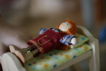 dollhouse doll lying on a bed