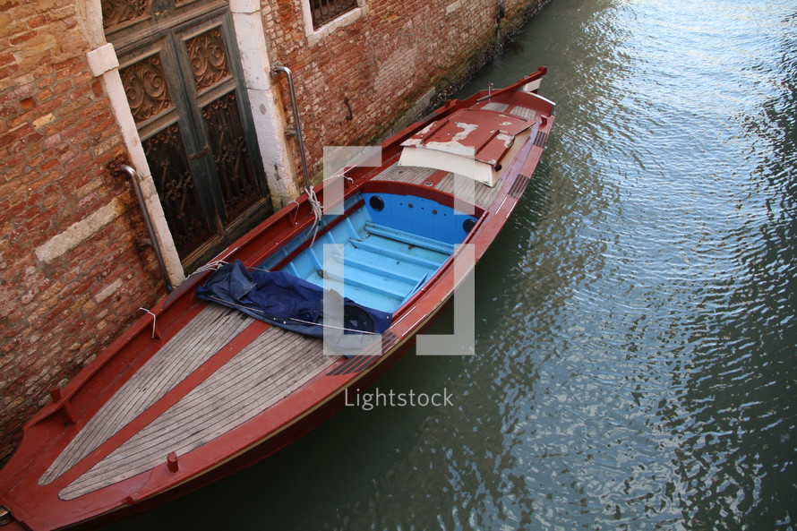 boat docked against a brick wall of a building in Venice