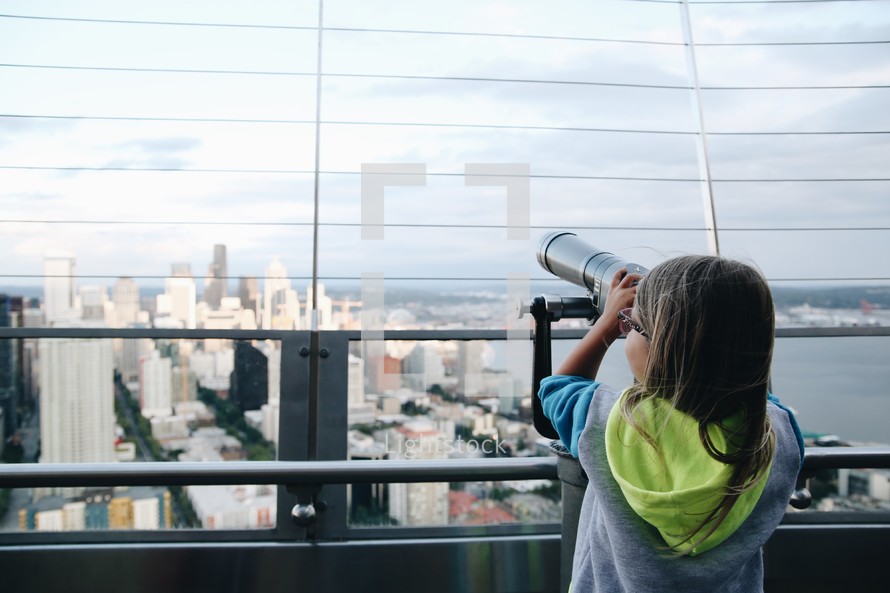 a girl looking through a telescope on the rooftop of a building in a city 
