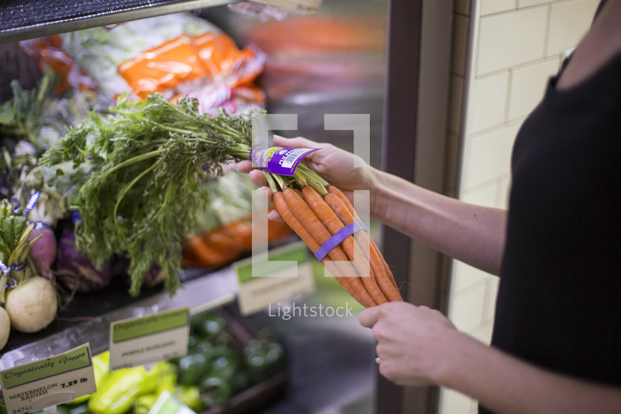 a woman getting carrots out of a refrigerator 