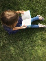a child reading in grass