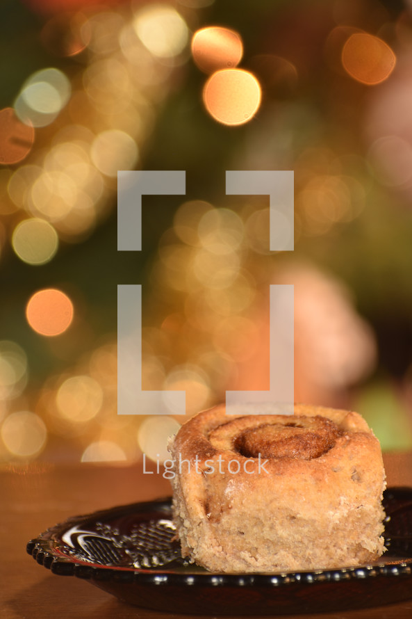 a vertical of a cinnamon roll with Christmas bokeh in the background