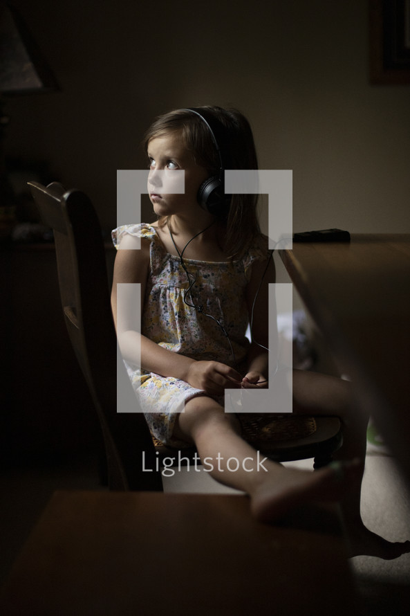 a girl listening to headphones sitting at a table 