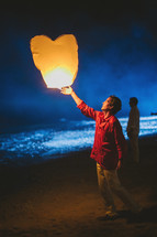 man releasing a heart shaped paper lantern 