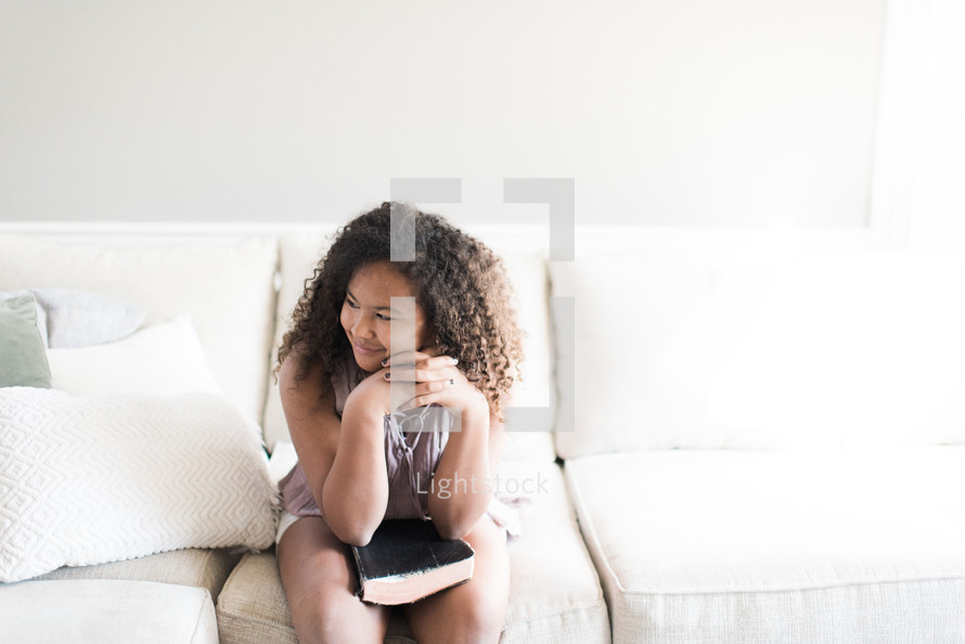 teen girl sitting on a couch with a Bible in her lap 