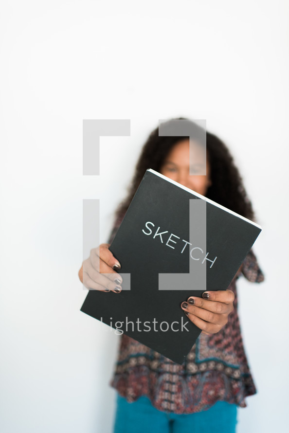 teen girl holding out a sketch book 