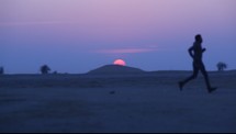 man running in a desert at sunset 