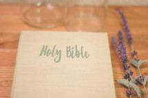 Holy Bible, lavender, and glass bottles on wood 