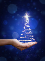 Christmas tree with light in hand on blue