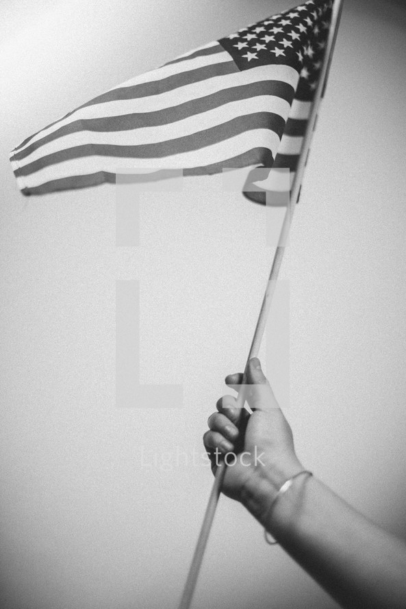 woman's arm holding up an American flag 