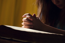 woman in prayer over the pages of a Bible 