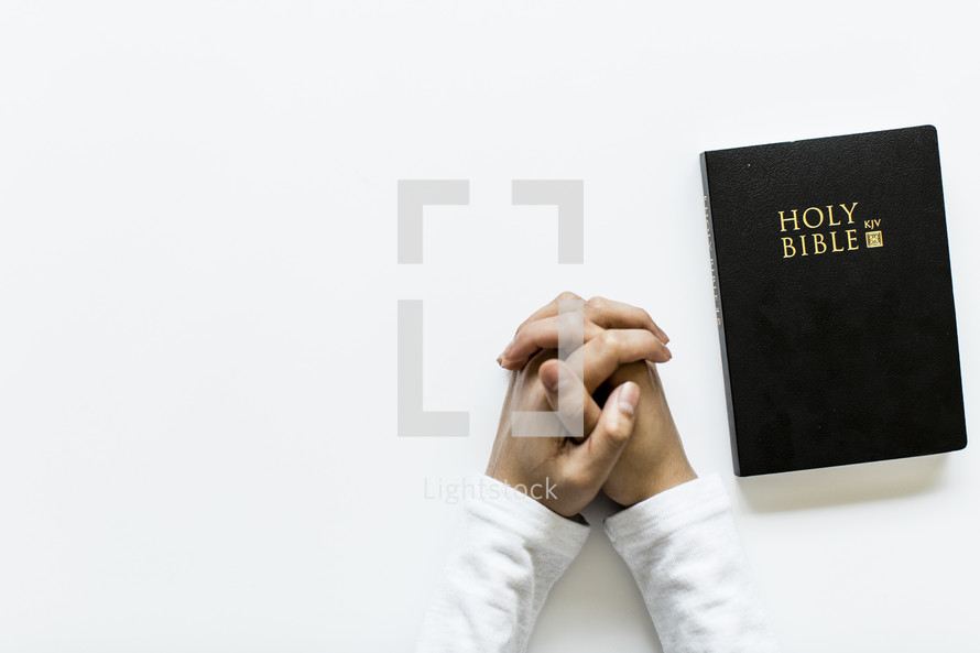 praying hands and a Holy Bible on white background 