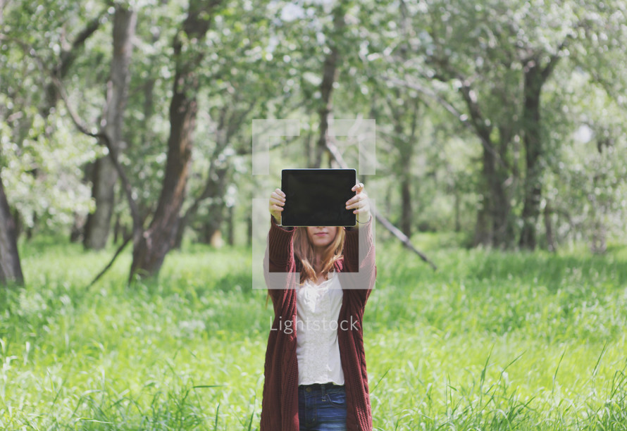 young woman outdoors holding up blank tablet - space for text