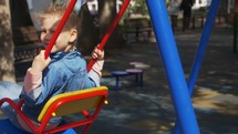 Little girl on a swings at a park. 