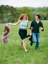 man and a woman running barefoot in a grass field 