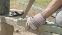 Man Hand-Sawing Wood at Construction Site