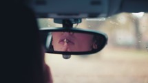 a sad woman alone in a car looking in a mirror