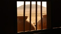 pottery pots through barred window in desert 
