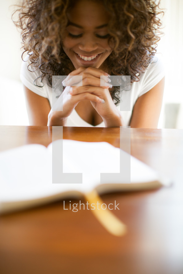 woman in prayer over the pages of a Bible