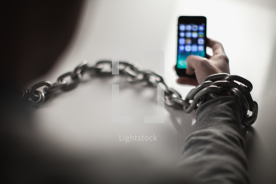 man bound in chains on a cellphone 