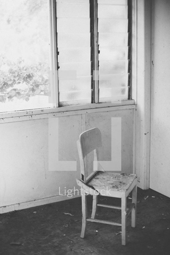 Chair in the corner of a room by the window.