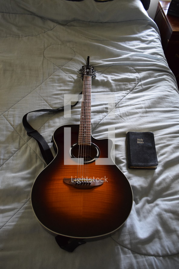 guitar and Bible on a bed 