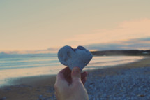 a hand holding up a heart shaped rock 
