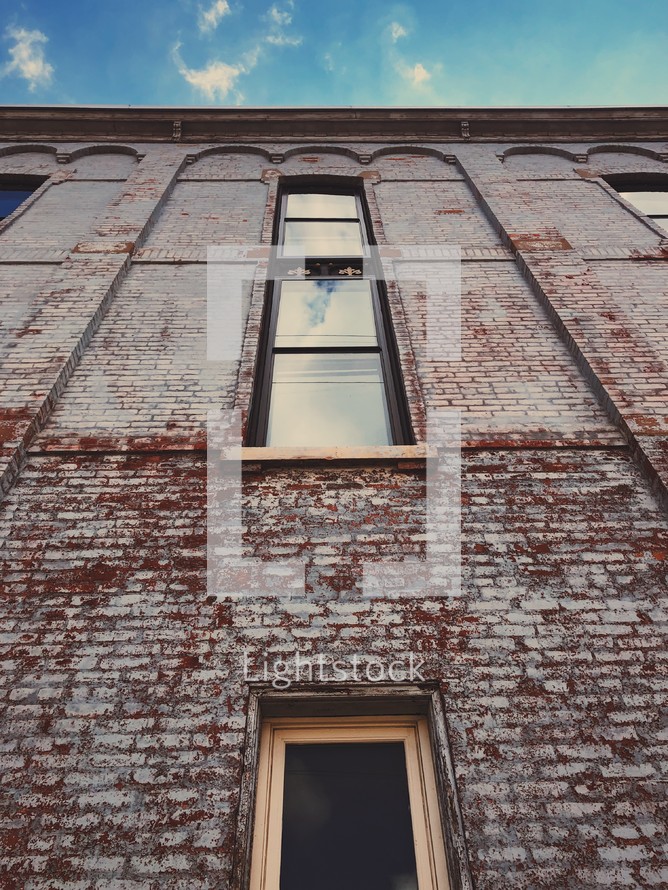 looking up at the side of a brick building with windows 