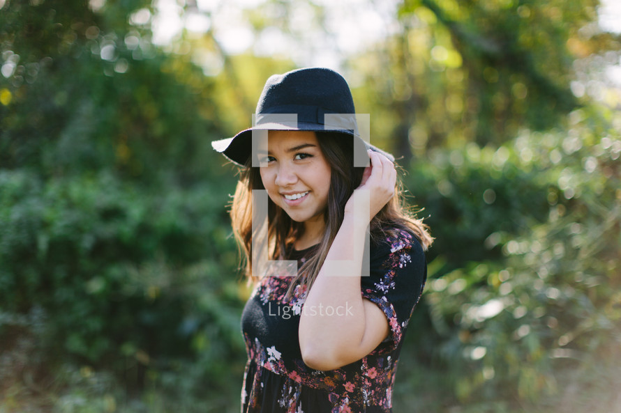 portrait of a teen girl in a hat standing outdoors 