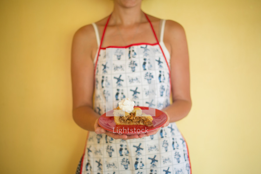 woman in an apron holding a slice of pie