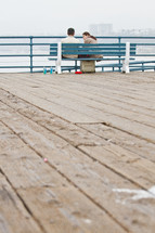 couple sitting on a bench on a pier 