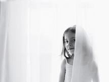a little girl behind a sheer curtain 