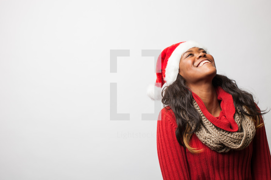 A woman in a santa hat looking up. 