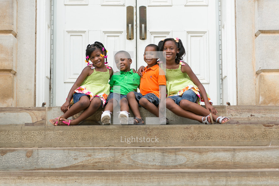 Happy siblings sitting on church steps