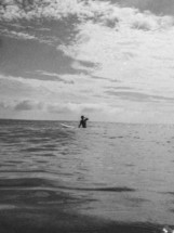 A black and white image of a surfer waiting for the next wave