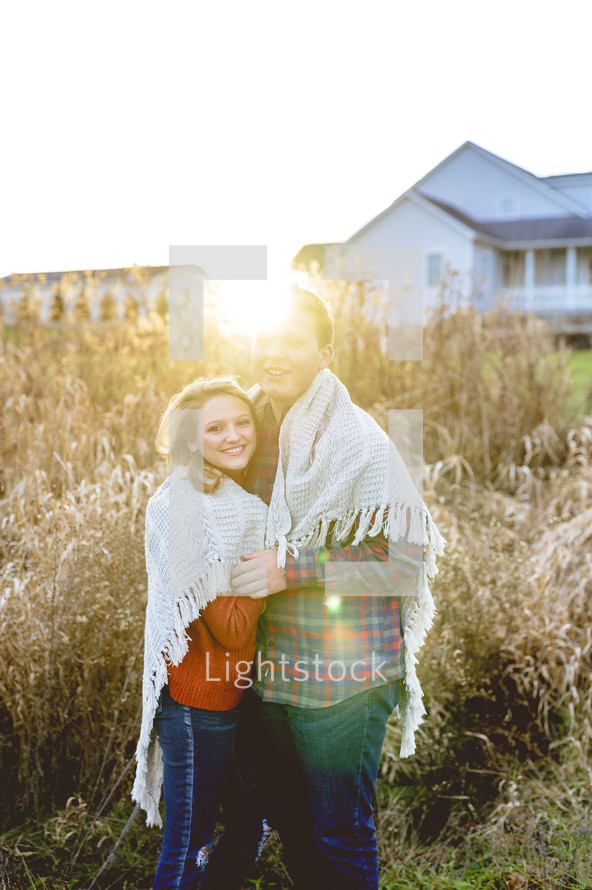 portrait of a couple wrapped in a blanket outdoors 