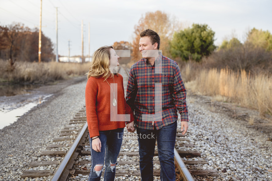 portrait of a couple standing in the middle of train tracks 