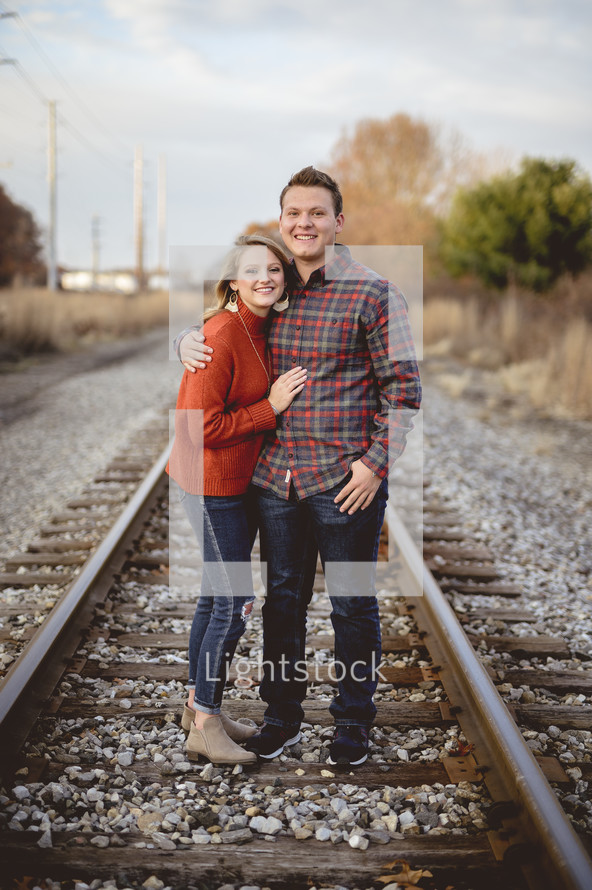 portrait of a couple standing on train tracks 